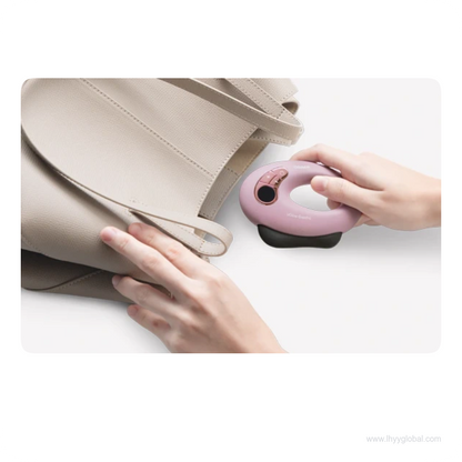 Hands holding a purple OSIM uGlow Guasha massager beside a beige handbag.