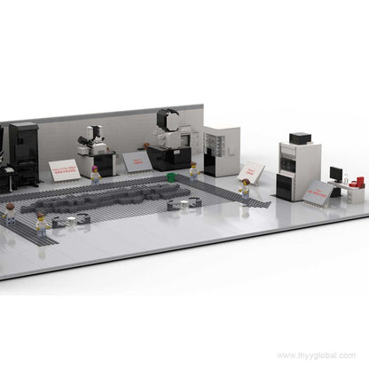 A detailed close-up of the control room in the Thermo Fisher Cryo-EM laboratory building block set, featuring two scientist minifigures seated at workstations with multiple monitors displaying simulated scientific data.